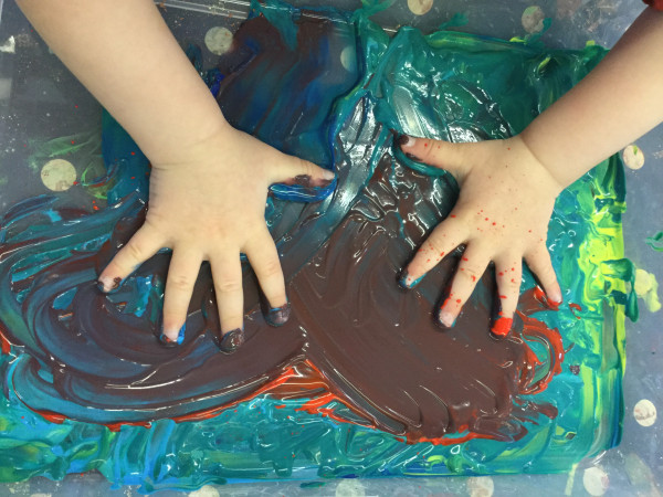 A child is playing with water colours at Alton College Nursery in Alton, Guildford