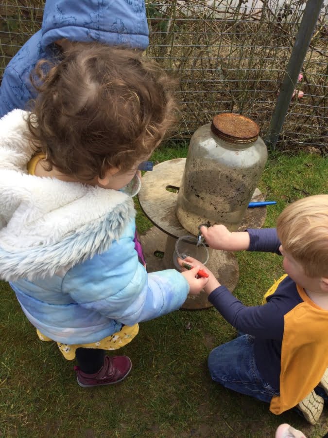 A kid is pouring water into a cup at Alton College Nursery in Alton, Guildford